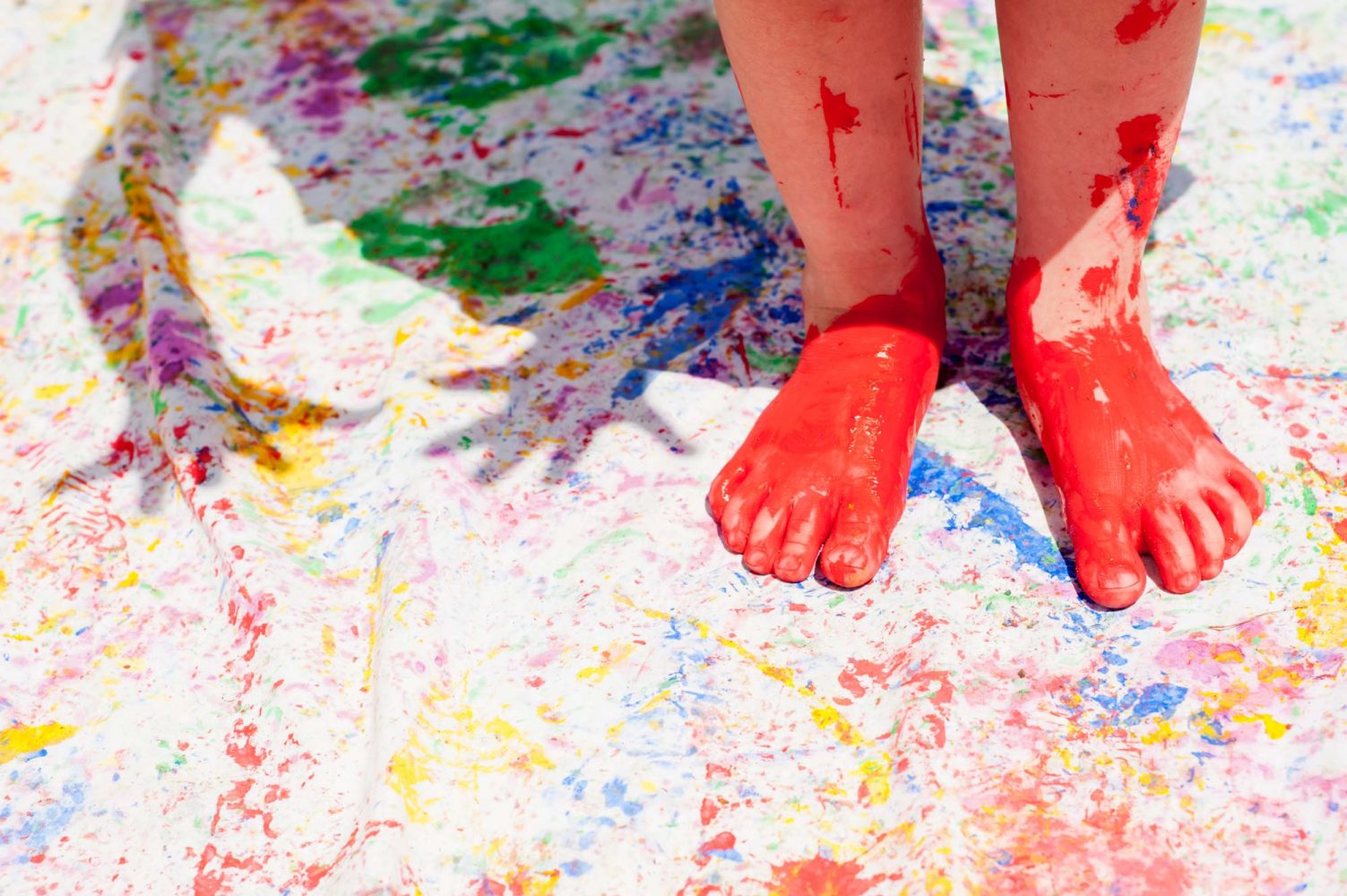 Child painting with feet outdoors