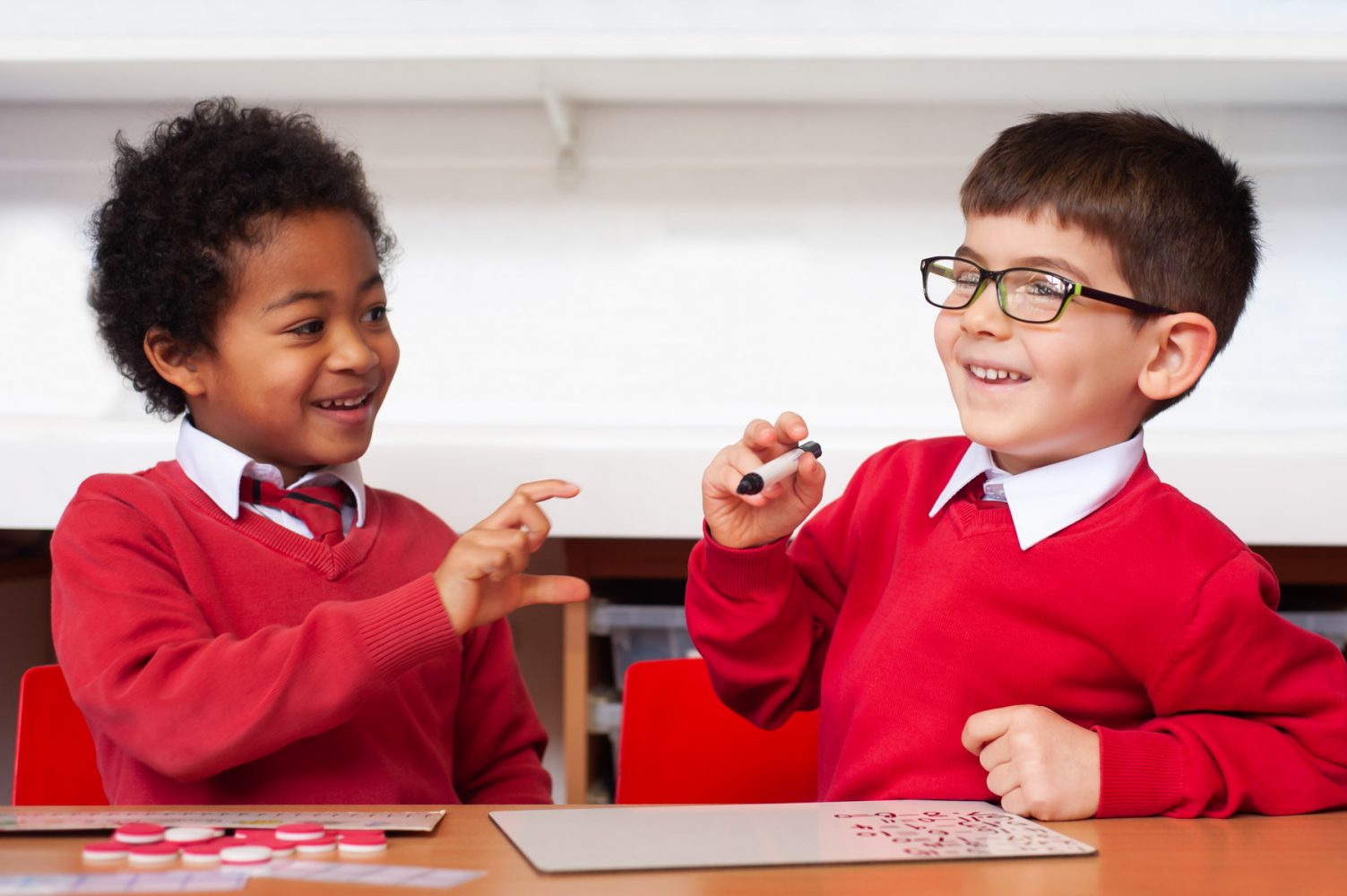 Primary school website photography of two pupils smiling at a desk