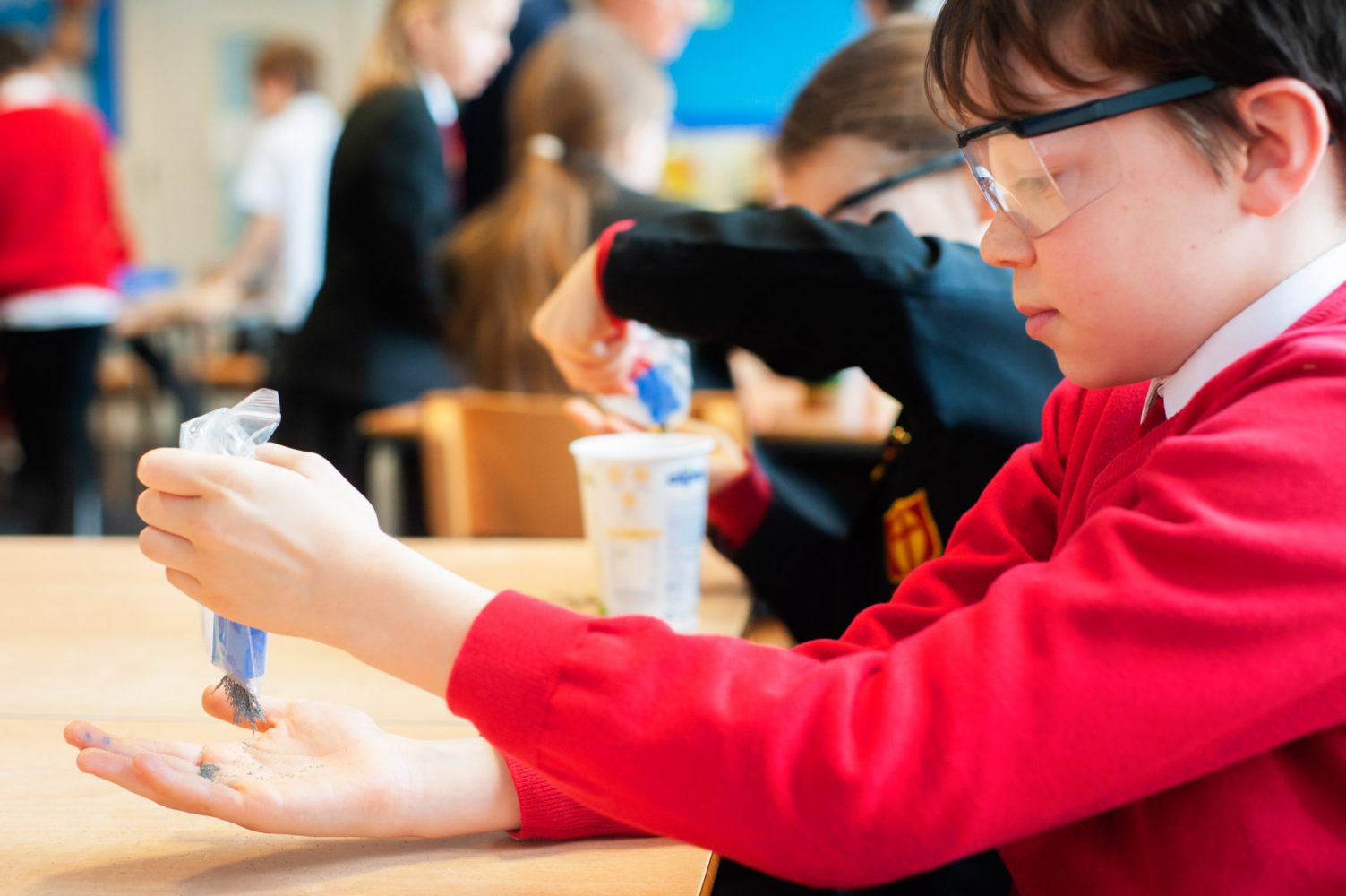 Primary school website photogrpahy of pupil using magnet and iron filings